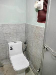 a bathroom with a white toilet and a window at jyoti dormitory in Varanasi