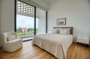 a bedroom with a bed and a chair and a window at Oasis Villa 3 in Khlorakas +19 photos