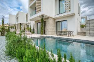 a house with a swimming pool in front of a house at Oasis Villa 3 in Khlorakas
