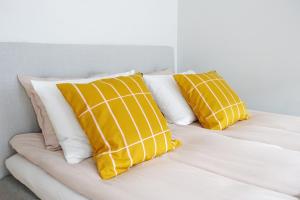 a bed with yellow and white pillows on it at Stylish Design Studio Next to The Parliament House in Helsinki