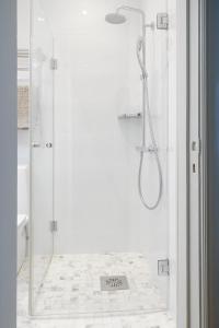 a white bathroom with a shower with a glass door at Stylish Design Studio Next to The Parliament House in Helsinki +22 photos