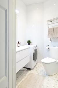 a white bathroom with a toilet and a sink at Stylish Design Studio Next to The Parliament House in Helsinki