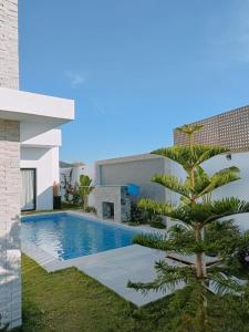 a palm tree next to a swimming pool next to a building at VILLA POOL Djerba Aghir AIR CONDITIONING - 5 BEDS in Aghīr