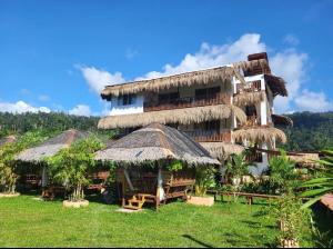 圣维森特La Palapa Inn Port Barton的茅草屋顶和草丛的大建筑