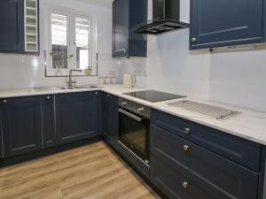 Una cocina con gabinetes azules y un fregadero. en 21 Taliesin Street, en Llandudno 14 fotos más