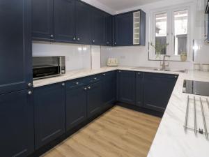 cocina con armarios azul marino y microondas en 21 Taliesin Street, en Llandudno