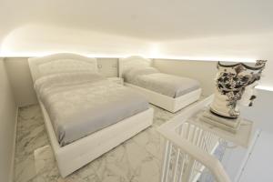 a white bedroom with two beds and a chair at Catania Luxury Apartments in Catania