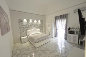 a white bedroom with a bed and a stone wall at Catania Luxury Apartments in Catania