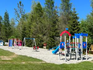 two children playing on a playground in the sand at Domki w Lesie Tylicz in Tylicz