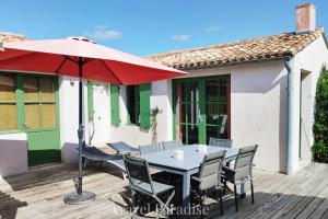 a table and chairs with a red umbrella on a deck at Villa Green Oaks in Rivedoux-Plage