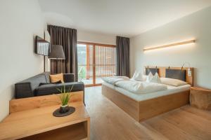 a hotel room with a bed and a couch at Gailerhof Boutique Hotel B&B Dolomites in Monguelfo