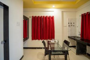 a dining room with red curtains and a glass table at Gapstays in Pune