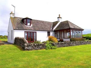 una casa bianca con un muro di pietra nel cortile di Allanhead Cottage a Kirkcudbright