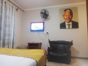 a bedroom with a bed and a clock and a chair at Parow city -Star Legend Lodge in Cape Town
