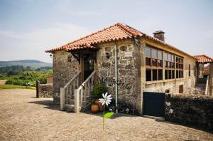 a stone house with a flower in front of it at Vila Margarida in Porreiras