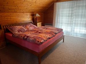 Un dormitorio con una cama con una pared de madera. en Chalupa Na Vyhlídce, en Sudoměř