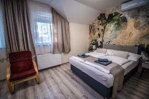 a bedroom with a large bed and a red chair at City Panzió in Szarvas