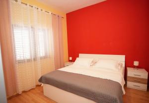 a bedroom with a bed with a red wall at Apartment Beky in Podstrana