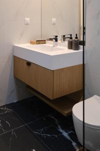 une salle de bain avec un lavabo et des toilettes dans l'établissement Brown I One Bedroom Apartment I One Cotroceni Park, à Bucarest