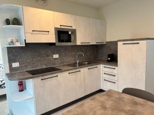 a kitchen with white cabinets and a sink and a microwave at Appartamento Rita in Pisogne