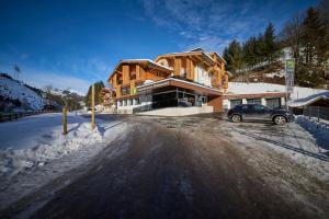 a car parked in front of a house in the snow at Jugendpension Müllauerhof in Saalbach Hinterglemm