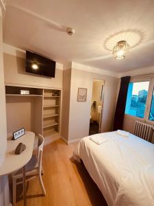 a bedroom with a bed and a table and a tv at Hôtel Anatole France in Toulouse