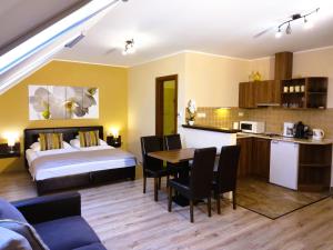 a hotel room with a bed and a table and a kitchen at Gellény Lux Apartman in Gyula