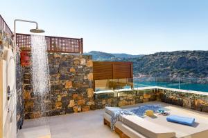 a bathroom with a jacuzzi tub with a stone wall at Daios Cove in Agios Nikolaos