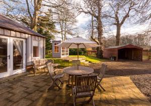 un patio avec une table, des chaises et un parasol dans l'établissement Luffness Castle Cottage, à Aberlady