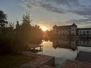 a sunset over a body of water with buildings at Művészház Nyaraló in Békésszentandrás