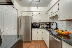 una cucina con mobili bianchi e un frigorifero in acciaio inossidabile di Nashville - 1808 State St #208 a Nashville