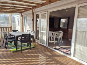 a screened in porch with a table and chairs at MH 201 AGREABLE et tout ÉQUIPÉ 2CH dont suite parentale et 2sdb avec vue sur foret dans camping 4 étoiles in Saint-Julien-en-Born