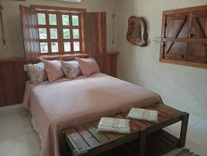 a bedroom with a large bed with two towels on it at Suítes Pirenópolis Piri in Pirenópolis