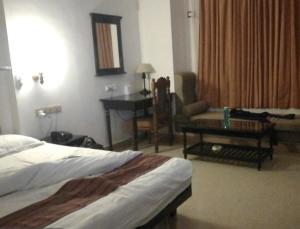 a hotel room with a bed and a table and a couch at Hotel Park International Varkala in Varkala