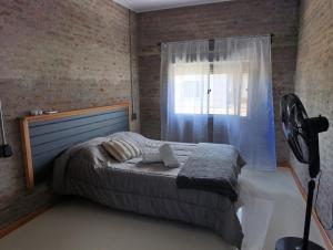 a bedroom with a bed with a fan and a window at Chacra LANATIVA in Poblado Echeverry