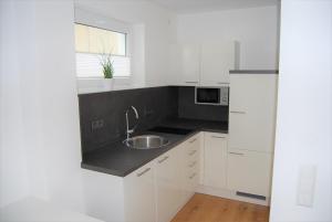a white kitchen with a sink and a microwave at Unter der Yburg Stetten in Stetten