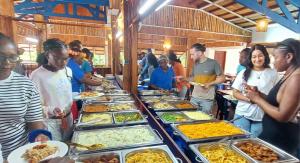 a group of people standing around a buffet of food at La Maringa El Magnifico in Libreville