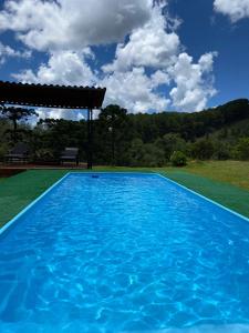 una piscina blu con gazebo di Cantinho de Campos a Campos do Jordão