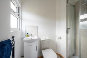 a white bathroom with a toilet and a sink at WestHill Beach Chalet, Riviere Towans in Hayle
