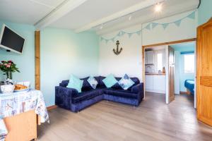 a living room with a blue couch and a table at WestHill Beach Chalet, Riviere Towans in Hayle +6 photos