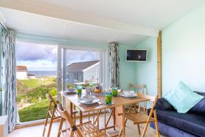 a living room with a table and chairs and a large window at WestHill Beach Chalet, Riviere Towans in Hayle