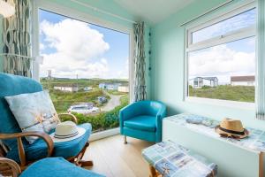 a living room with a large window and a blue chair at WestHill Beach Chalet, Riviere Towans in Hayle