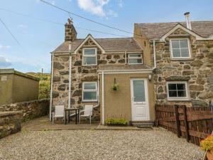 ein Cottage aus Stein mit einem Tisch und Stühlen davor in der Unterkunft Moonlight Cottage in Pwllheli