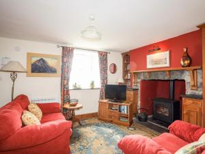 ein Wohnzimmer mit einem roten Sofa und einem Kamin in der Unterkunft Moonlight Cottage in Pwllheli