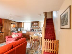 ein Wohnzimmer mit einem roten Sofa und einer Küche in der Unterkunft Moonlight Cottage in Pwllheli