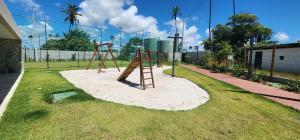 a playground with a swing set in the grass at Porto de Galinhas - Muro Alto, Malia Beach Experience in Ipojuca