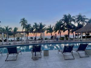 a resort swimming pool with chairs and palm trees at Apartment In Camino Al Mar with Amazing View of the Ocean, Beach and Swimming Pool, 2 Rooms in Mazatlán
