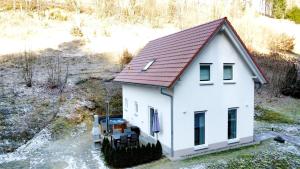a small white house with a red roof at Frankenwald Chalets - Ferienhaus mit privaten Whirlpool in Wilhelmsthal