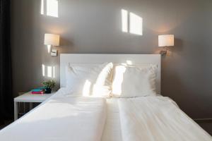 a white bed with two pillows and a table with two lamps at Apartment Hotel Lindeneck in Erfurt