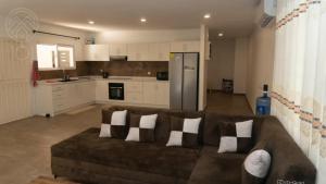 a living room with a brown couch and a kitchen at Nelly Residence in Paramaribo